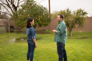 Image of a male and female neighbors discussing irrigation as water is delivered from a back yard valve in Tempe, Ariz.