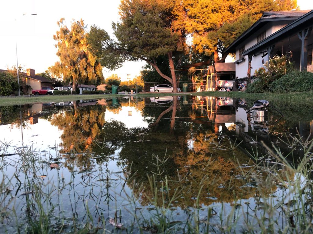 Image shows a yard and home surrounded by shallow water.