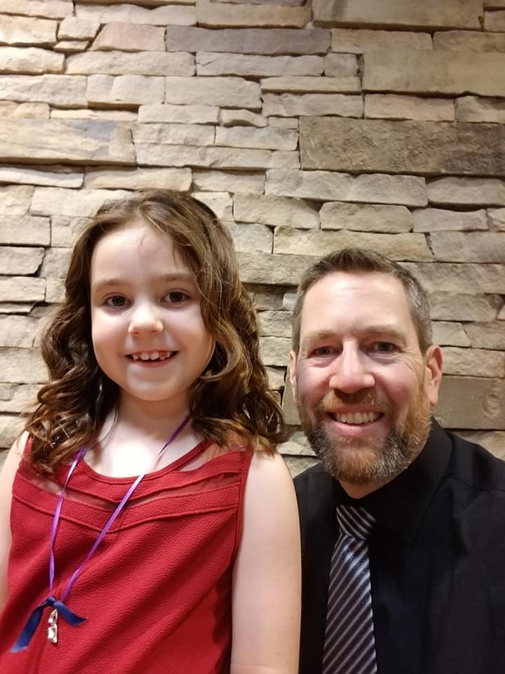 Image shows a father and daughter smiling at the camera.