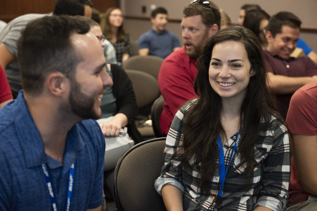 Image shows a male and female intern chatting at event.